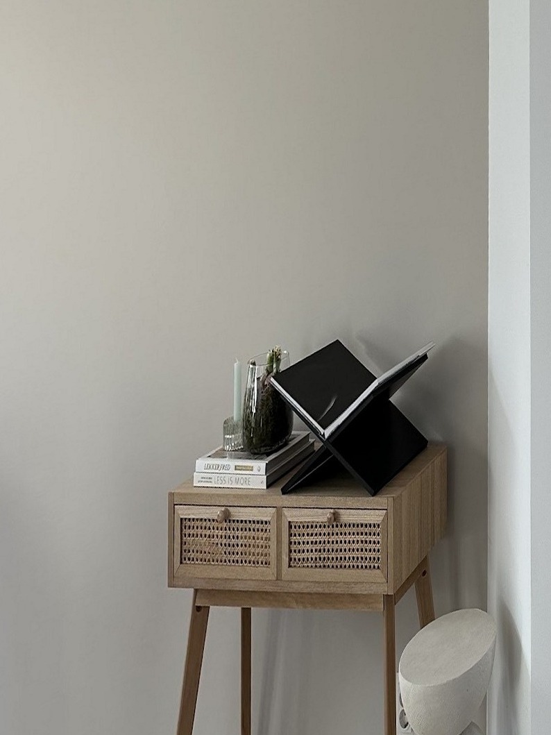 Eetkamer na oplevering: strak gestucte wand met een houten sidetable met boeken, de hoek van de kamer rechts in beeld